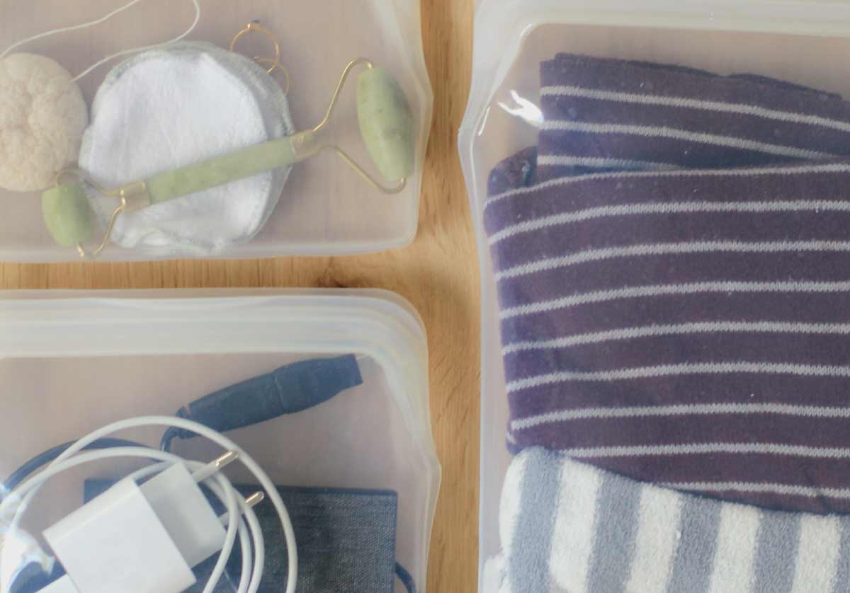 drie reusable food bags gevuld met items zoals kleding, opladers en toiletartikelen