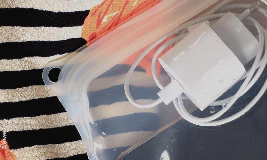 telefoon en oplader in een reusable food bag van lless tegen de achtergrond van een strandtas