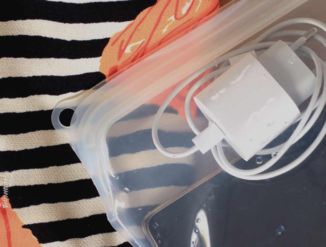 telefoon en oplader in een reusable food bag van lless tegen de achtergrond van een strandtas