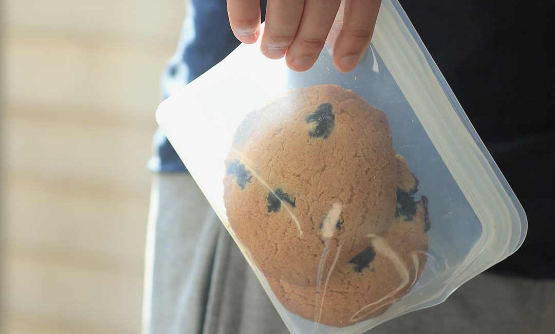 man houdt reusable food bag vast met zelfgebakken koekjes erin
